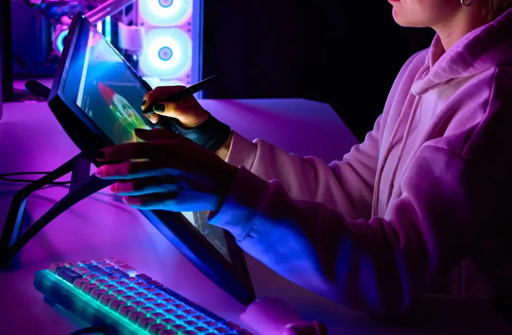 カラフルなライトに照らされたパソコン環境で作業している人物の様子。